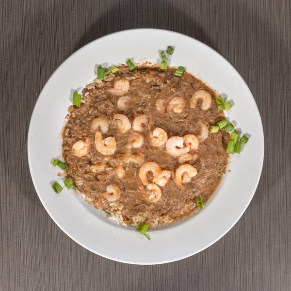 Overhead view of shrimp gumbo with rice and green onions on a white plate.